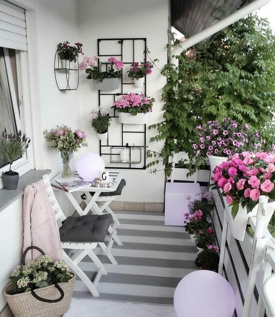 kwiaty na balkonie petunie i bratki, szaro-biały dywan, biały stolik z krzesłami