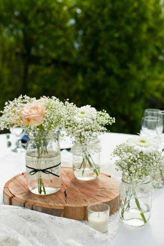 rustykalny stół w ogrodzie obrus i słoiki z kwiatami