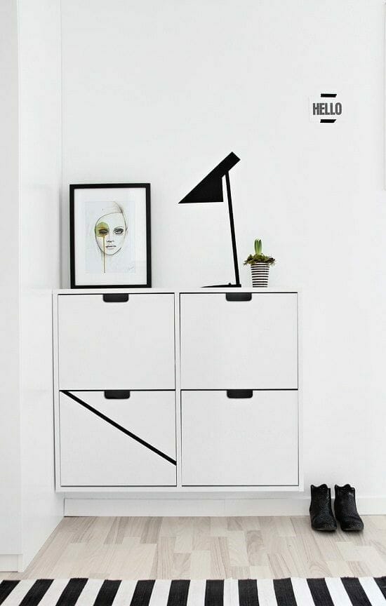 biały geometryczny z grafiką w czarnej ramce i czarną lampą z dywanem w czarno-białe pasy i jasnymi panelami