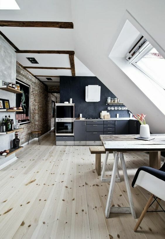 adaptacja poddasza na kuchnię i salon z drewnianą podłogą i biało-szarymi ścianami, ceglastą ścianą w przedpokoju i drewnianymi belkami