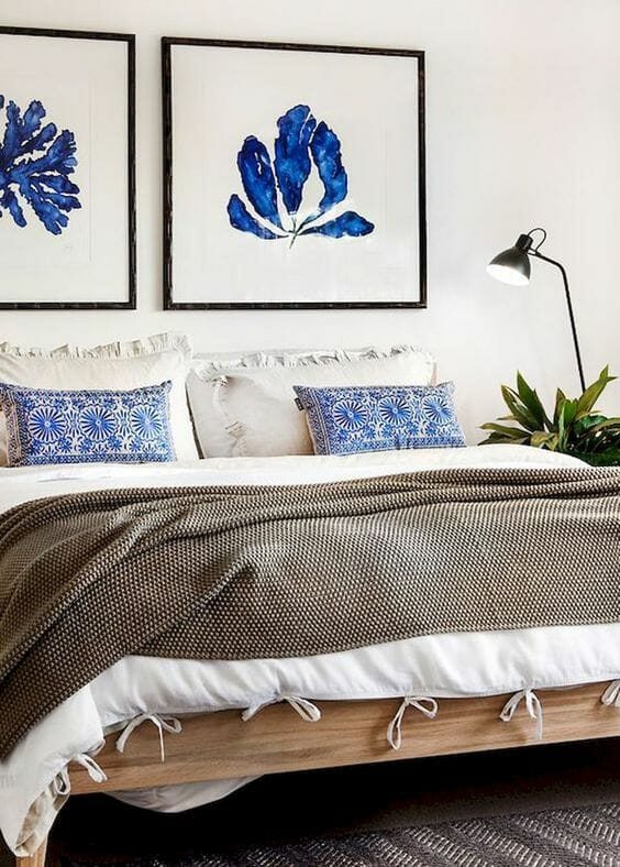 jasna sypialnia z akwarelą obrazami kwiatów nad łóżkiem i białą pościelą