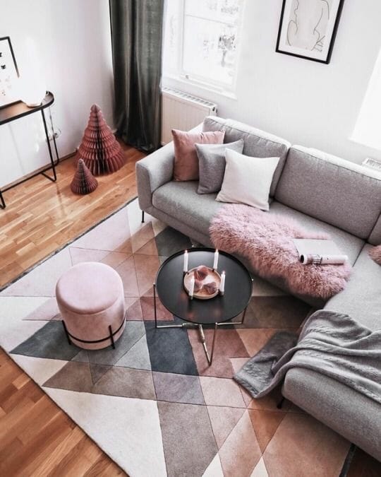 biały salon z szarą kanapą i różowymi dodatkami