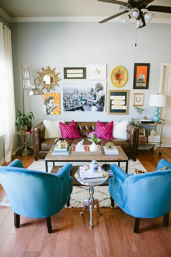 szary salon ze skórzaną kanapą i niebieskimi fotelami i różowymi poduszkami