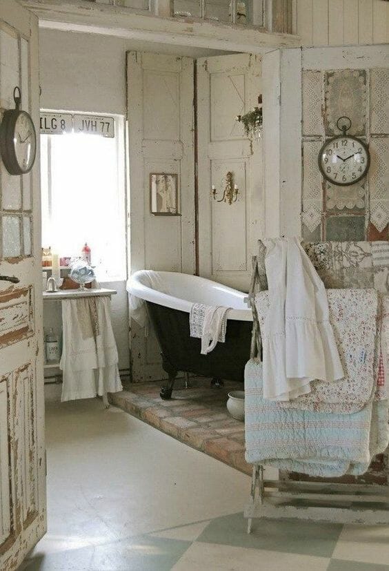 łazienka w stylu shabby chic drewno bielone postarzane drzwi metalowy zegar wolnostojąca wanna na nóżkach